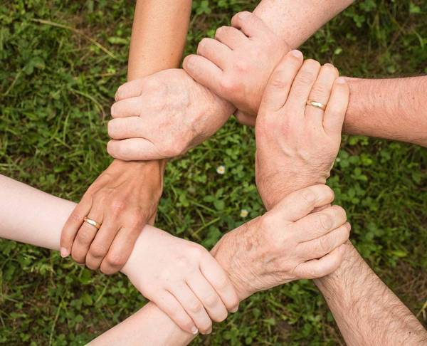 junge und alte Hände halten sich im Kreis